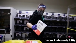 U.S. -- Election worker Gareth Fairchok removes ballots from a sorting machine as vote-by-mail ballots for the August 4 Washington state primary are processed at King County Elections in Renton, Washington on August 3, 2020.
