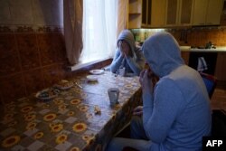 Chechen men who fled persecution from Chechnya due to their sexual-orientation, sit around a table in their flat in Moscow on April 17, 2017. / AFP PHOTO / Naira DAVLASHYAN