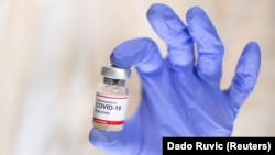 FILE PHOTO: A woman holds a small bottle labelled with a "Coronavirus COVID-19 Vaccine" sticker in this illustration taken, October 30, 2020.