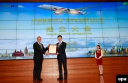 China -- Vladislav Masalov, (L) the Sukhoi Civil Aircraft Company (SCAC) President and chairman of China-Russia Commercial Aircraft International Corporation Limited (CRAIC), takes the business license from Chen Xuejun (C), Chief of Shanghai Administratio