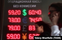 Russia -- People walk past a screen displaying foreign currency exchange rates outside a currency exchange office in Moscow, April 9, 2018