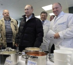 Russia -- businessman Yevgeny Prigozhin, right, smiles as he shows Russian President Vladimir Putin, center, around his factory which produces school meals