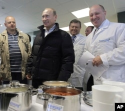 Russia -- businessman Yevgeny Prigozhin, right, smiles as he shows Russian President Vladimir Putin, center, around his factory which produces school meals
