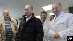 Russia -- businessman Yevgeny Prigozhin, right, smiles as he shows Russian President Vladimir Putin, center, around his factory which produces school means