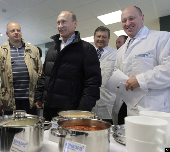 Russia -- businessman Yevgeny Prigozhin, right, smiles as he shows Russian President Vladimir Putin, center, around his factory which produces school meals