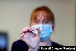FILE PHOTO: A member of the staff holds the Pfizer/BioNTech COVID-19 vaccine at the Abercorn House Care Home in Hamilton, Scotland, Britain December 14, 2020.