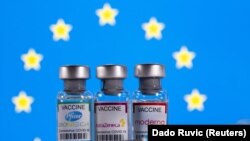 FILE PHOTO: Vials with Pfizer-BioNTech, AstraZeneca, and Moderna coronavirus disease (COVID-19) vaccine labels are seen in front of a European Union (EU) flag in this illustration picture taken March 19, 2021.