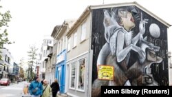 FILE PHOTO: People walk past artwork on the side of a shop as the outbreak of the coronavirus disease (COVID-19) continues in Reykjavik, Iceland, September 3, 2020. 