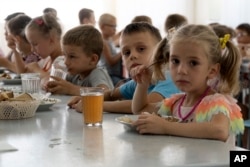 Children from an orphanage in Ukraine's Donetsk region eat a meal at a camp in Zolotaya Kosa, a settlement on the Sea of Azov in Russia's Rostov region, on July 8, 2022. (AP)
