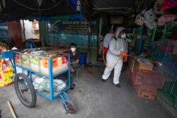 A worker sprays disinfectant as a precaution against the new coronavirus near a fruit vendor at Chatuchak Market in Bangkok, Thailand, on March 20, 2020.