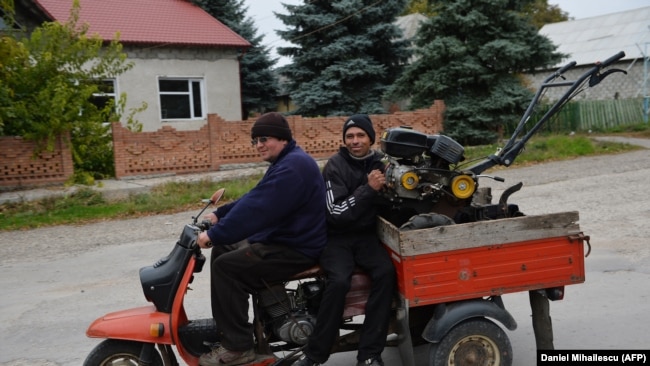 Moldova -- People ride a tricycle motorbike in Dobrogea village next to Balti, Moldova on October 10, 2013.