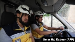 SYRIA -- Members of a Syrian civil defense team known as The White Helmets sit in an ambulance after receiving an alert in the rebel-held northern Syrian city of Idlib, August 26, 2018