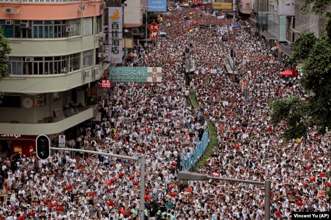 Protesters march along a downtown street against the proposed amendments to an extradition law in Hong Kong Sunday, June 9, 2019