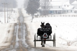 An Amish wagon makes its way north on County Road 1353 during a light snowfall near Ashland, Ohio, U.S. February 1, 2021. Tom E. Puskar/Times-Gazette.com/USA TODAY NETWORK via REUTERS.
