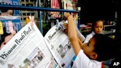 A boy hangs up copies of the English-language Phnom Penh Post at a newsstand in Phnom Penh on January 8, 2008.(AP)