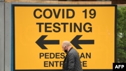 A pedestrian walks past a sign directing members of the public to a Covid-19 testing center in Bolton, England, on May 28, 2021. 