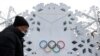 A worker walks in front of an installation with the Olympic Rings on January 19, 2022, near The National Stadium, also known as the Bird's Nest, where the opening and closing ceremonies of Beijing 2022 Winter Olympics will be held. (Carlos Garcia Rawlins/Reuters)