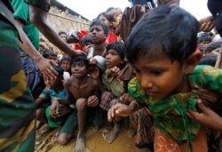 Rohingya refugee children struggle as they wait to receive food outside the distribution center at Palong Khali refugee camp near Cox's Bazar, Bangladesh, on Nov. 17, 2017.