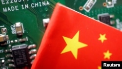 FILE PHOTO: A Chinese flag is displayed next to a "Made in China" sign seen on a printed circuit board with semiconductor chips, in this illustration picture taken February 17, 2023. (REUTERS/Florence Lo/Illustration/File Photo)