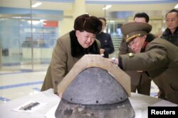 North Korean leader Kim Jong Un examiners a warhead tip of a ballistic missile after an alleged simulated test of the missile’s atmospheric re-entry capability, March 15, 2016.