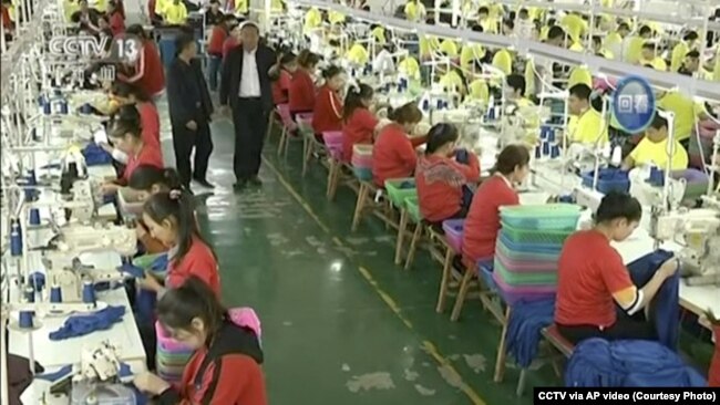 CHINA – In this file image from undated video footage run by China's CCTV, Muslim trainees work in a garment factory at the Hotan Vocational Education and Training Center in Hotan, Xinjiang.