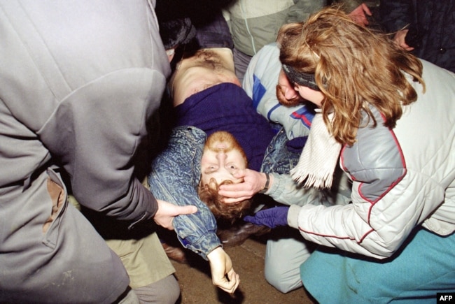Lithuania -- A dead Lithuanian pro-independence supporter has his eye opened by one of his comrades before being taken away in Vilnuis, January 13, 1991