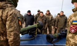 Ukrainian President Volodymyr Zelensky examines weapons as he attends tactical military exercises held by the country's armed forces at a training ground in the Rivne Region on February 16, 2022.