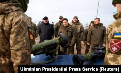 Ukrainian President Volodymyr Zelensky examines weapons as he attends tactical military exercises held by the country's armed forces at a training ground in the Rivne Region on February 16, 2022.