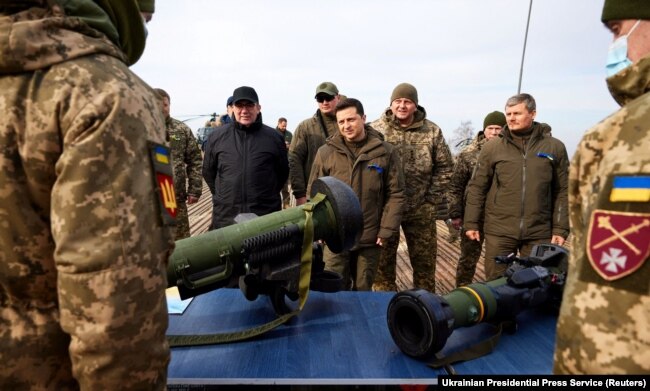Ukrainian President Volodymyr Zelensky examines weapons as he attends tactical military exercises held by the country's armed forces at a training ground in the Rivne Region on February 16, 2022.