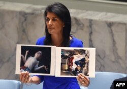 U.S. -- US Ambassador to the UN, Nikki Haley holds photos of victims as she speaks as the UN Security Council meets in an emergency session at the UN, New York, April 5, 201