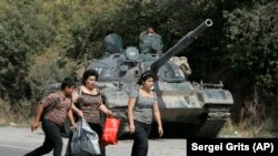 GEORGIA -- Georgian refugees are seen walking past a Russian armoured vehicle in the village of Igoeti, 50 kilometers (31 miles) from Tbilisi, August 16, 2008