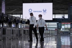 Staffs wearing protective masks to help curb the spread of the coronavirus walk in the empty ticketing area at Narita International Airport in Narita, Japan, on Tuesday, June 1, 2021.