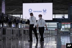 Staffs wearing protective masks to help curb the spread of the coronavirus walk in the empty ticketing area at Narita International Airport in Narita, Japan, on Tuesday, June 1, 2021.