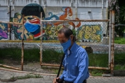 A man wearing a face mask walks past a coronavirus-related mural in downtown Caracas, Venezuela on July 21, 2020, after the government intensified a nationwide lockdown.
