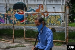 VENEZUELA – A man wearing a face mask walks past a coronavirus-related mural in downtown Caracas on July 21, 2020, after the government intensified a nationwide lockdown.