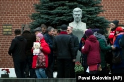 RUSSIA -- An elderly woman holds a portrait of the Soviet founder Vladimir Lenin, as people lay flowers at the monument to Soviet leader Joseph Stalin on Red Square to mark the 100th anniversary of Komsomol, the Soviet-era communist youth organization.
