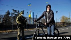UKRAINE -- Ukrainian border guards secure the checkpoint as a man crosses with his bicycle between the Kyiv-controlled territory and occupied areas in the war-torn east, in the town of Shchastya in the Luhansk region, November 10, 2020