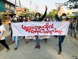 Students hold a banner and flash the three-finger salute as they take part in a protest against Myanmar’s junta in Mandalay on May 10, 2021. (Reuters)