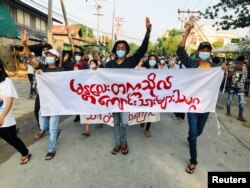 Students hold a banner and flash the three-finger salute as they take part in a protest against Myanmar’s junta in Mandalay on May 10, 2021. (Reuters)