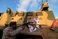 LIBYA -- A member of Libyan National Army (LNA) commanded by Khalifa Haftar, points his gun to the image of Turkish President Tayyip Erdogan hanged on a Turkish military armored vehicle, which LNA said they confiscated during Tripoli clashes, in Benghazi.