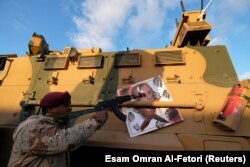 LIBYA -- A member of Libyan National Army (LNA) commanded by Khalifa Haftar, points his gun to the image of Turkish President Tayyip Erdogan hanged on a Turkish military armored vehicle, which LNA said they confiscated during Tripoli clashes, in Benghazi.