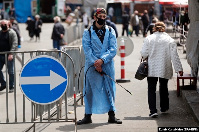 GEORGIA -- A man wearing a protective face mask waits to disinfect carts at a street market in Tbilisi, April 27, 2020
