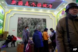 Visitors look at a booth near the words "Xinjiang is a good place" during the 11th Xinjiang Agricultural Produce Beijing Fair held in Beijing on Saturday, Dec. 5, 2020. (AP Photo/Ng Han Guan)