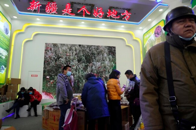 Visitors look at a booth near the words "Xinjiang is a good place" during the 11th Xinjiang Agricultural Produce Beijing Fair held in Beijing on Saturday, Dec. 5, 2020. (AP Photo/Ng Han Guan)