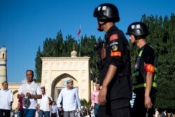 This picture taken on June 26, 2017 shows police patrolling as Muslims leave the Id Kah Mosque after the morning prayer on Eid al-Fitr in the old town of Kashgar in China's Xinjiang Uighur Autonomous Region.