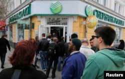 People stand in line as they wait to enter Russian Sberbank in Simferopol, Crimea, April 7, 2014.