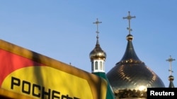 Russia -- The logo of Russia's top crude producer Rosneft is seen on a gasoline station near a church in the southern city of Stavropol, December 9, 2014