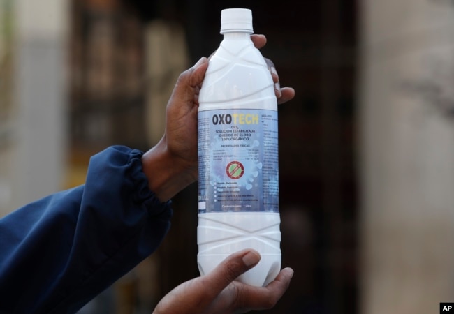 A man shows a bottle of chlorine dioxide he purchased in a bazaar in La Paz, Bolivia, Saturday, Aug. 8, 2020.