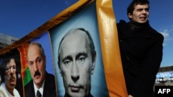 Opposition activists hold a banner with portraits of Russian Prime Minister Vladimir Putin, former Libyan leader Muammar Qaddafi and Belarus President Alexander Lukashenko at a rally in Pushkin Square, Moscow, in March of 2011. (AFP)