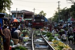 A train makes its way slowly past vendors as they remove their goods from the tracks at the railway bazaar near Tha Ye Zay railway station in Mandalay, Myanmar on May 19, 2019.